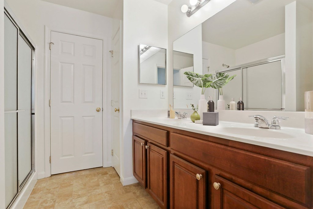 A bathroom with a white door and a brown vanity.