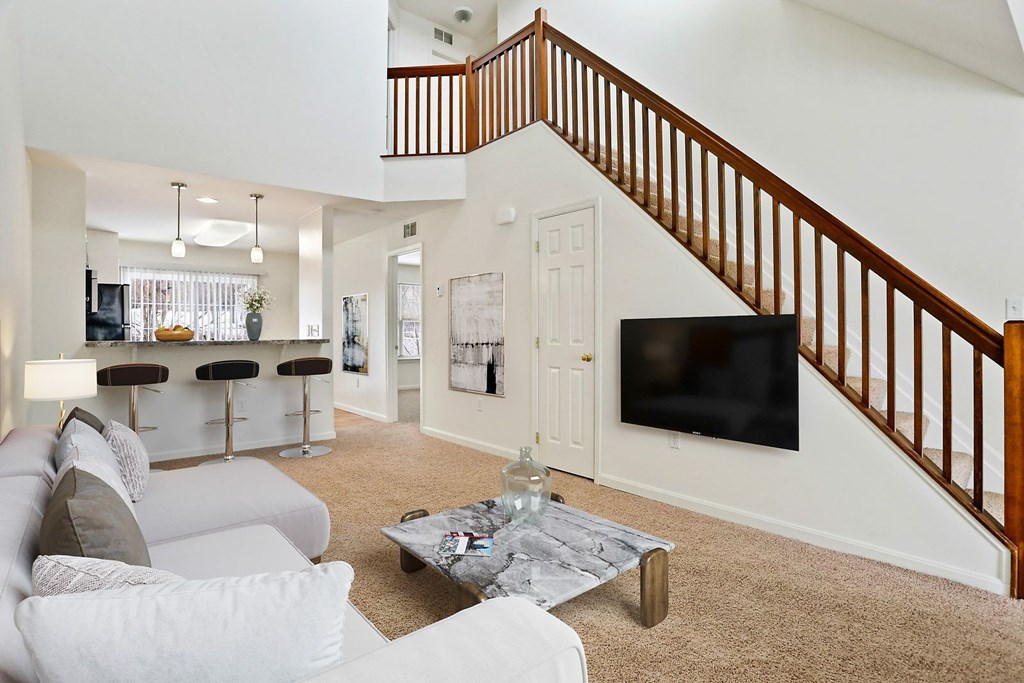 A living room with a white couch and a wooden staircase.