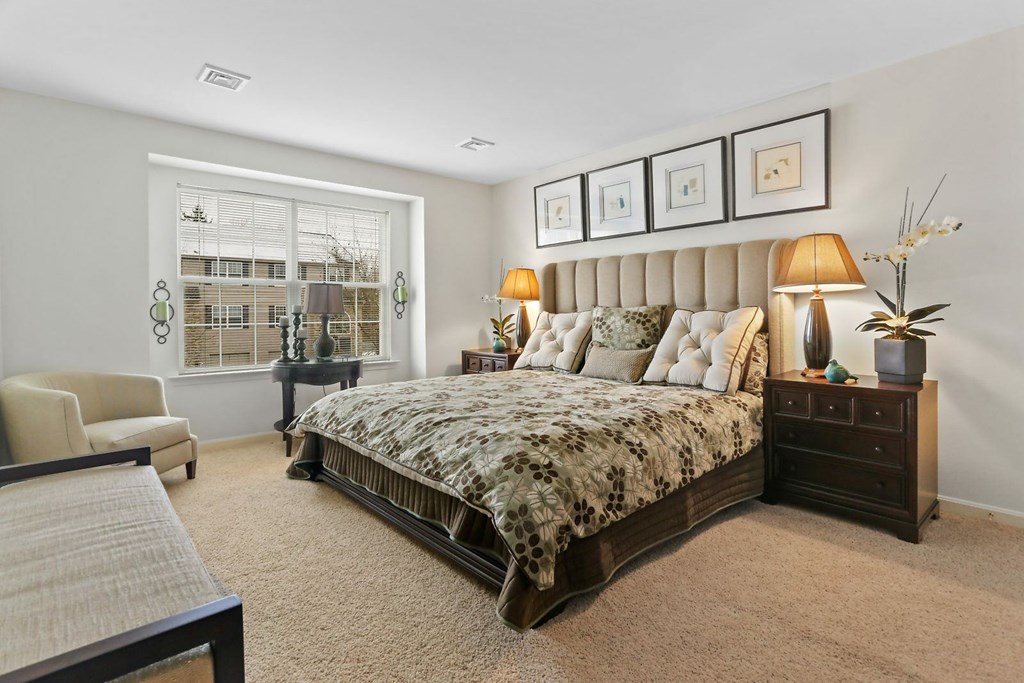 A bedroom with a large bed and a chair.