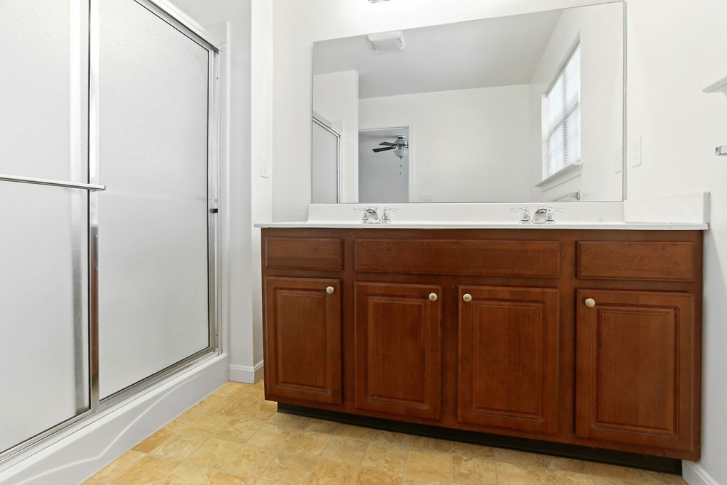 A bathroom with a white door, a brown cabinet, and a mirror.