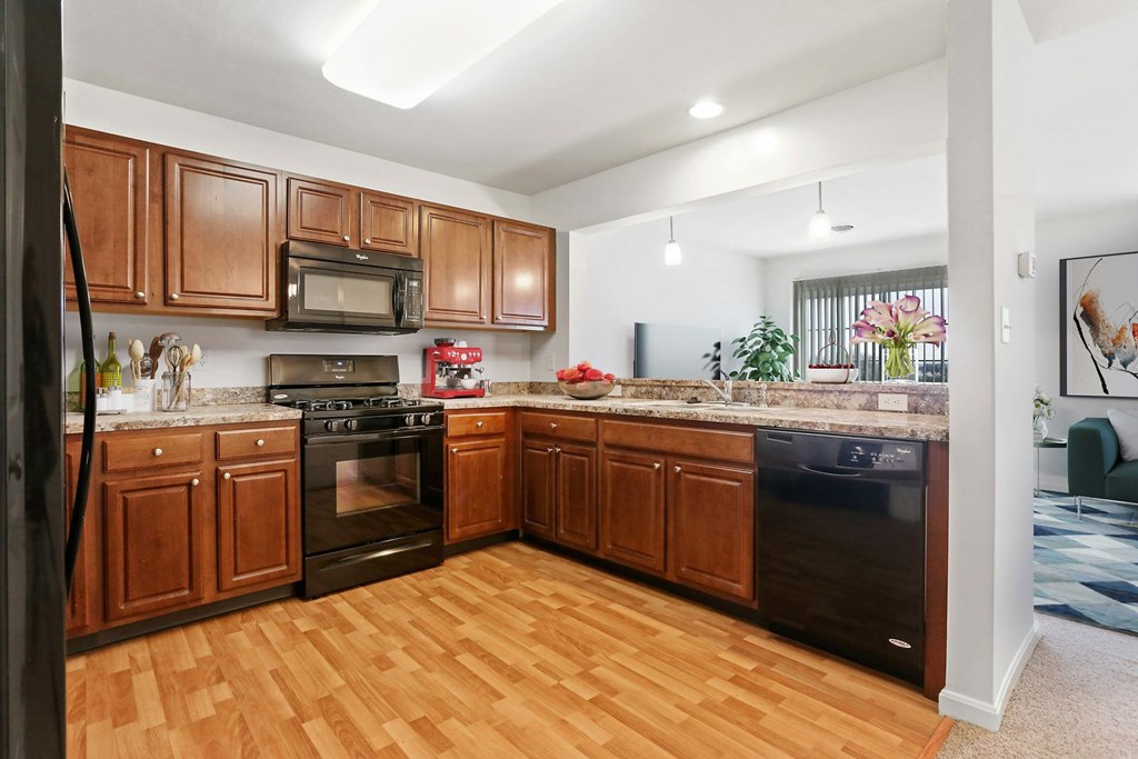 A kitchen with wooden cabinets and a black refrigerator.