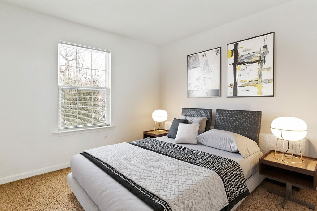 A bedroom with a large bed and two lamps.