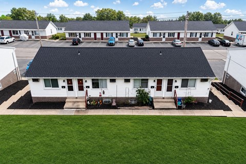 A white building with a black roof is surrounded by other similar buildings.