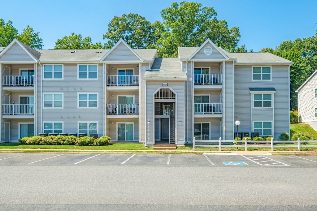 A large apartment building with a parking lot in front.
