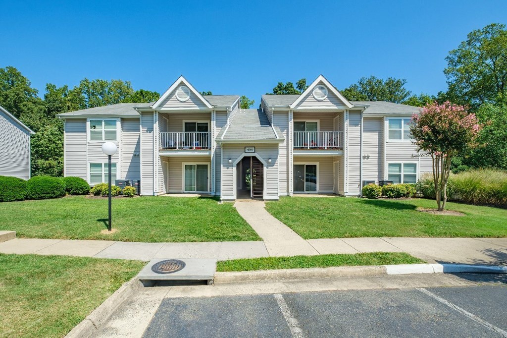 A large two-story apartment building with a front lawn and a parking lot in front.