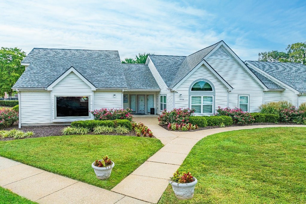 A white house with a grey roof and a green lawn.