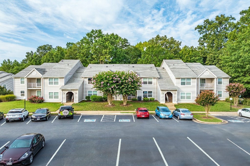 A parking lot with cars and apartment buildings in the background.