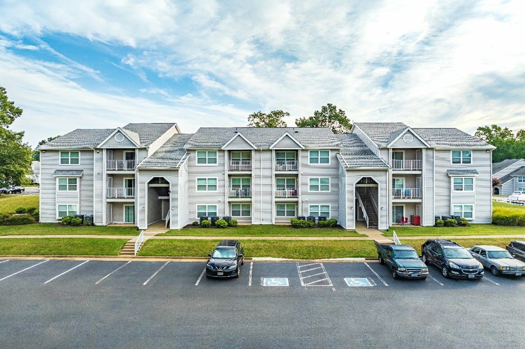 A row of townhouses with cars parked in front.