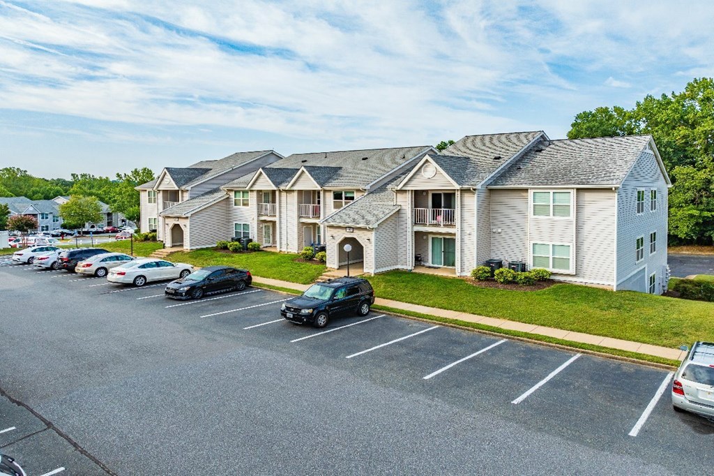 A parking lot in front of a building with cars parked.