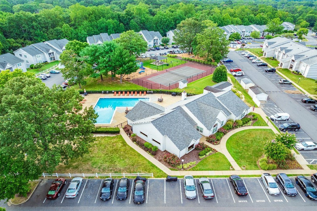 A bird's eye view of a residential area with houses, cars, and a swimming pool.