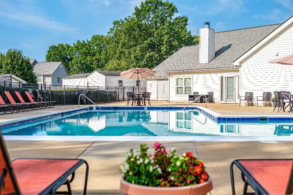 A pool with a table and chairs and a house in the background.