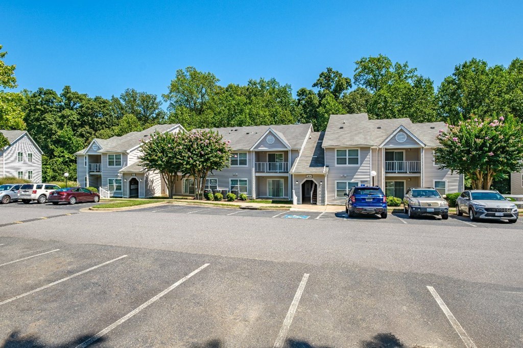 A parking lot in front of a building with cars parked.