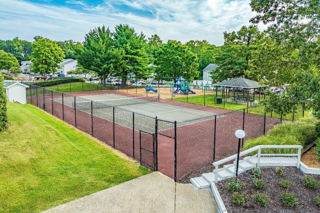 A tennis court surrounded by a fence and trees.