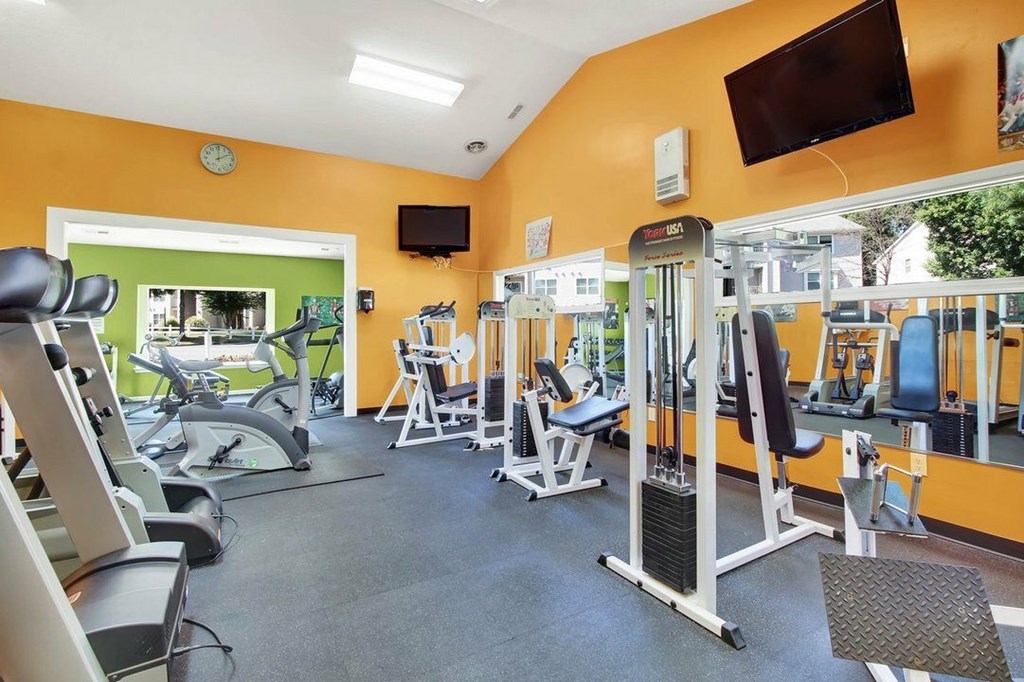 A gym with orange walls and various exercise machines.