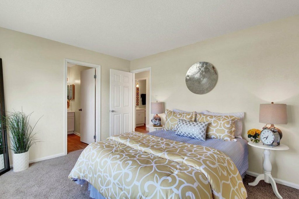 A bedroom with a large bed and a mirror on the wall.