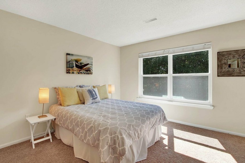 A bedroom with a bed, nightstand, and window.