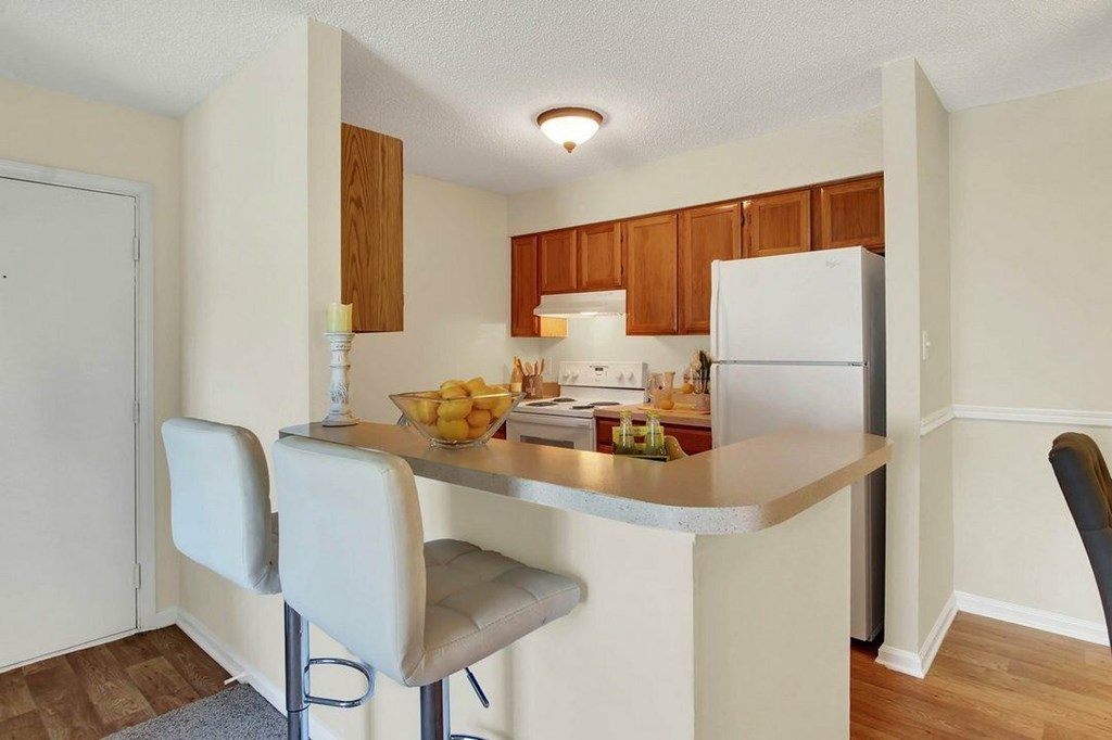 A kitchen with a white refrigerator, white countertop, and white chairs.