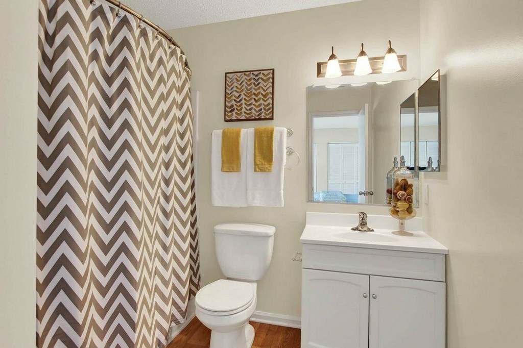 A bathroom with a chevron shower curtain and a white toilet.