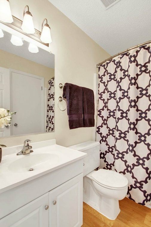 A white bathroom with a brown and white shower curtain.