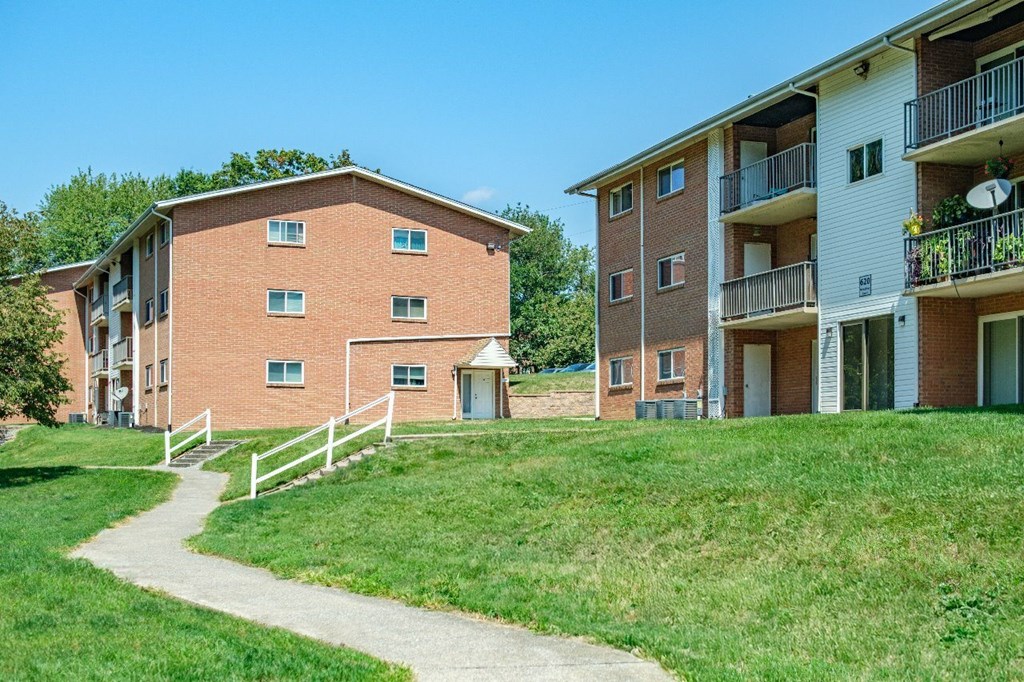 A building with a red brick exterior and a white balcony with plants on it.