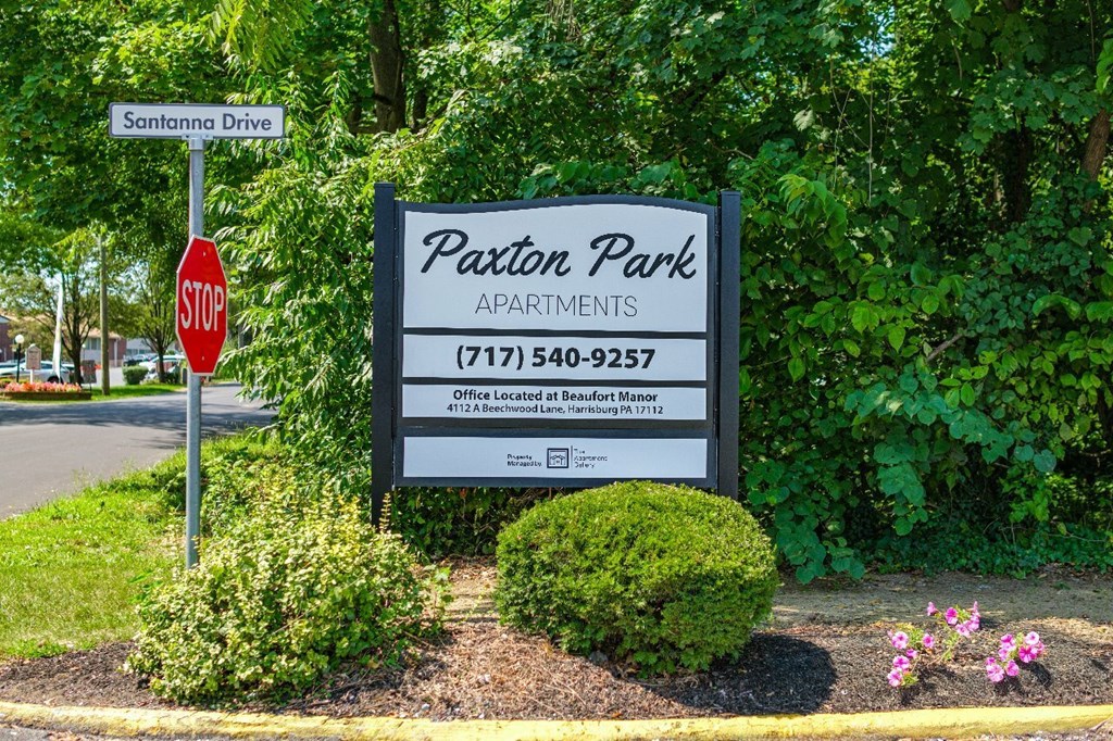 A sign for Paxton Park Apartments is displayed in front of a tree.