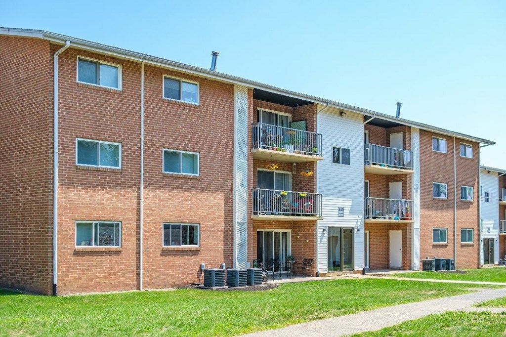 A red brick apartment building with a balcony on the second floor.