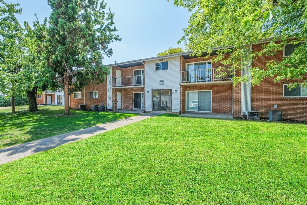 A grassy area in front of a brick apartment building.