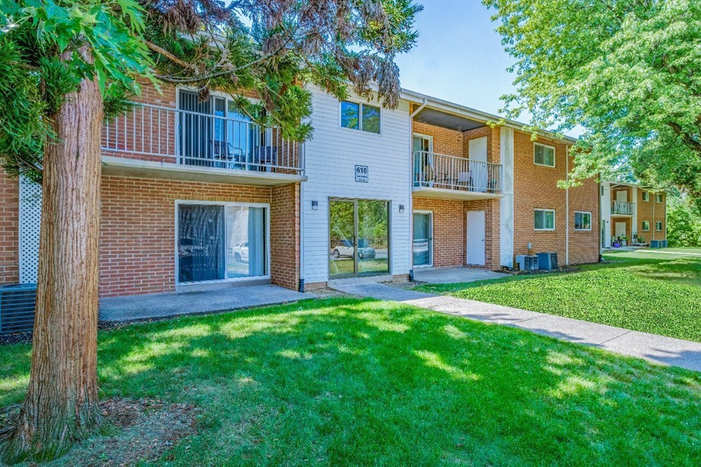 A tree is in front of a building with a balcony.