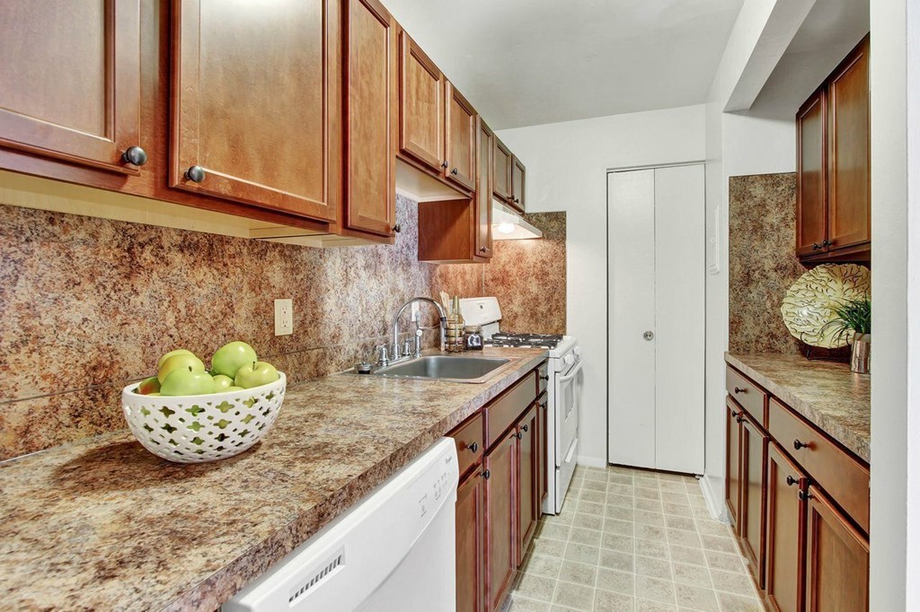 A kitchen with brown cabinets and a marble countertop.