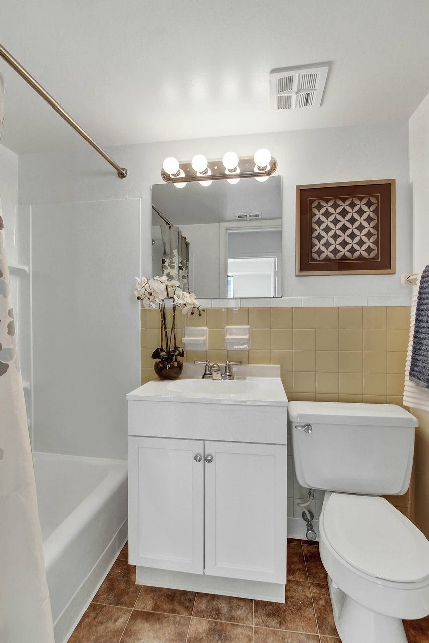 A white bathroom with a toilet, sink, and mirror.