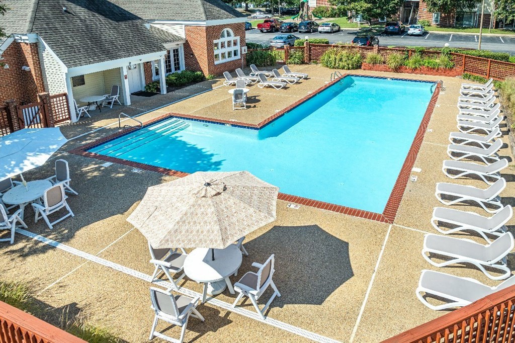 A pool surrounded by chairs and umbrellas.