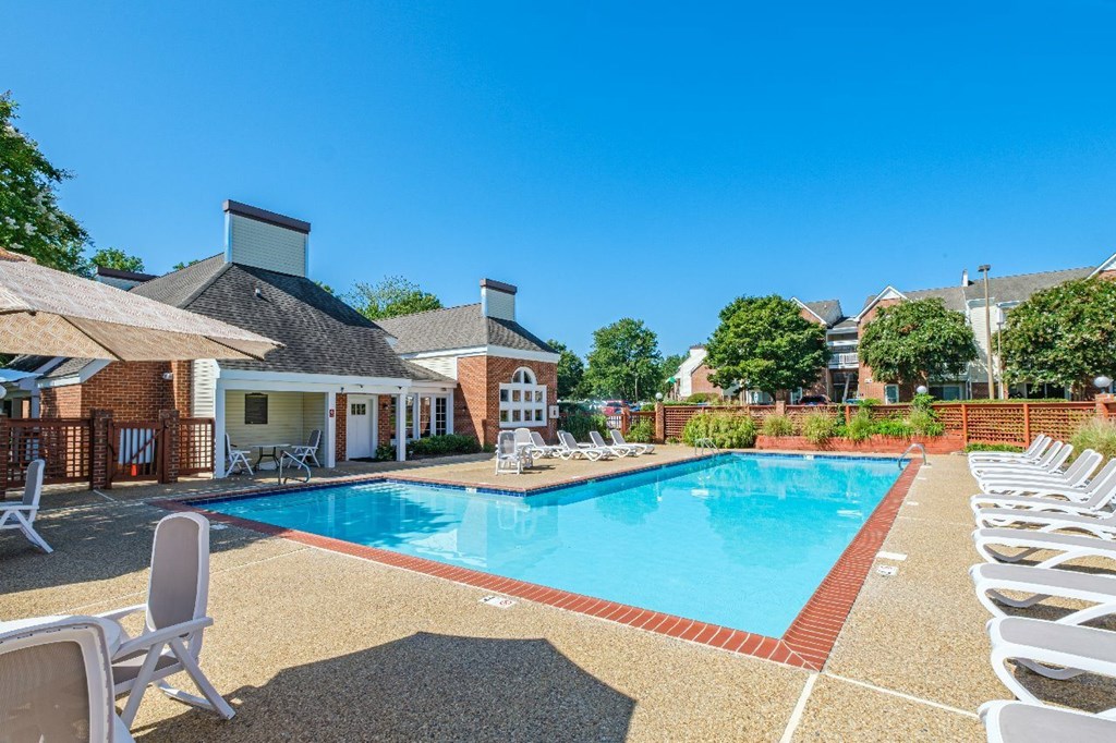A pool surrounded by lounge chairs and umbrellas.