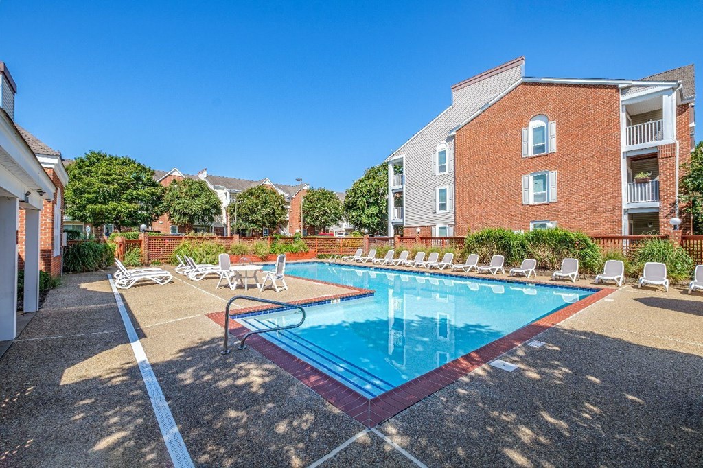 A swimming pool surrounded by lounge chairs and trees.