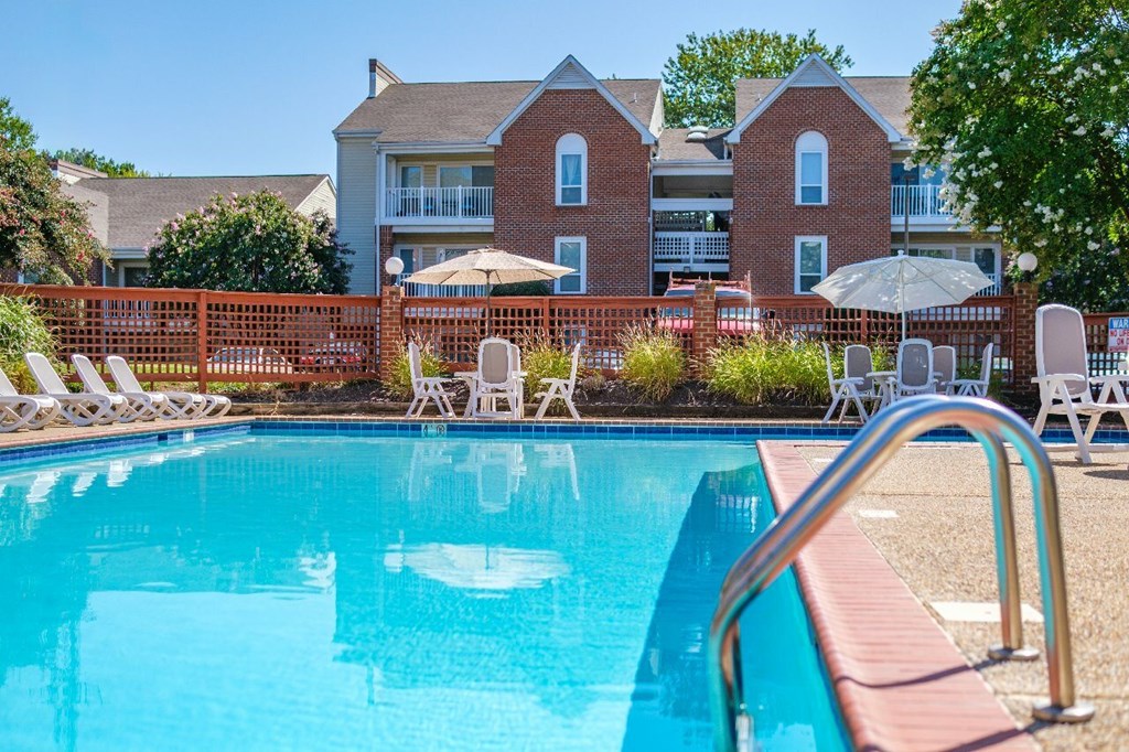 A swimming pool with a red fence and white chairs.