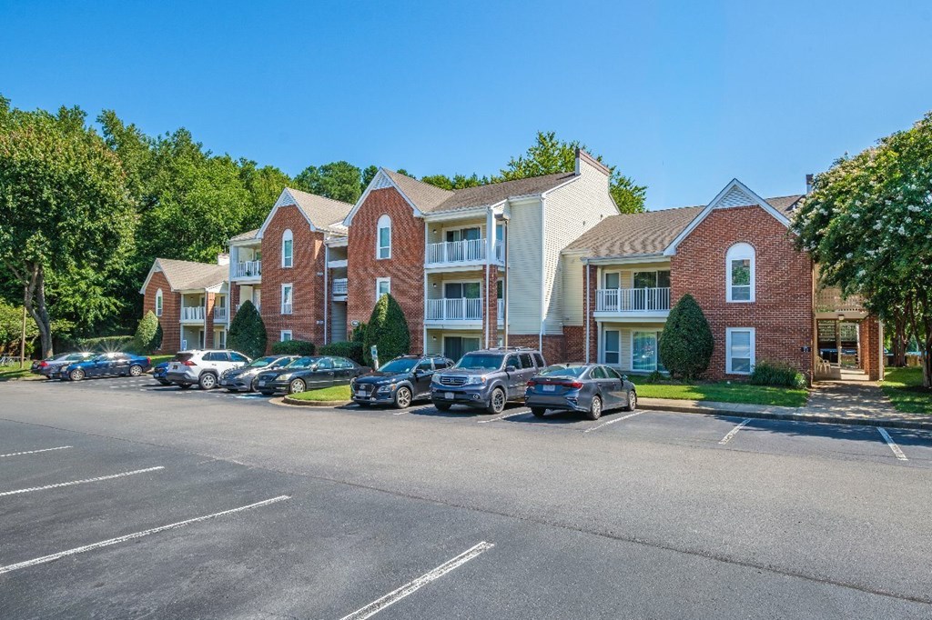 A parking lot in front of a red brick apartment building.
