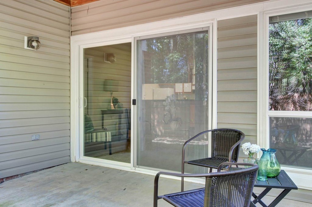 A patio with a table and chairs and a vase of flowers.
