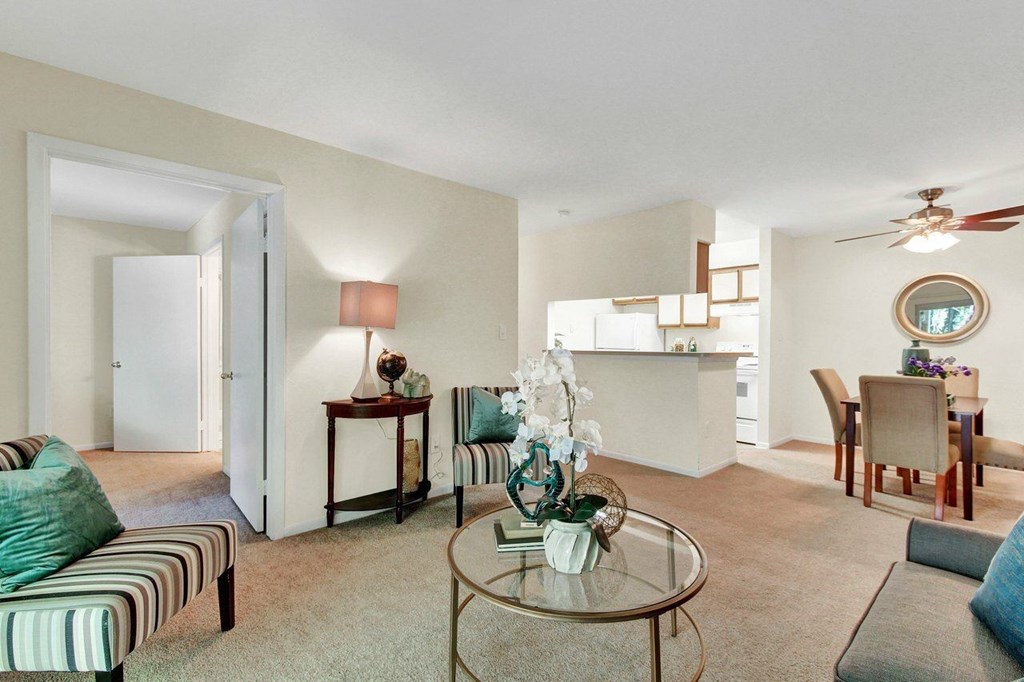 A living room with a glass table and striped couch.