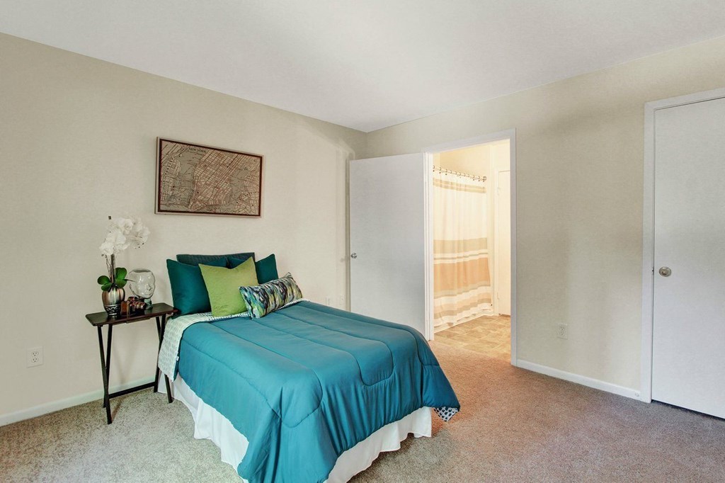 A bedroom with a bed, nightstand, and a painting on the wall.