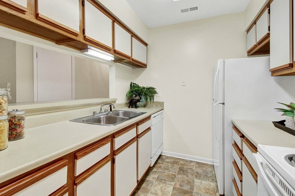 A kitchen with white appliances and wooden cabinets.