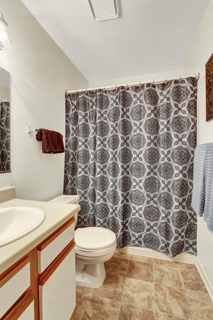 A bathroom with a toilet, sink, and shower curtain.