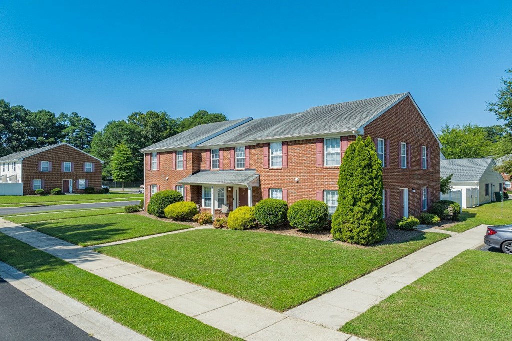 A red brick house with a white car parked in front.