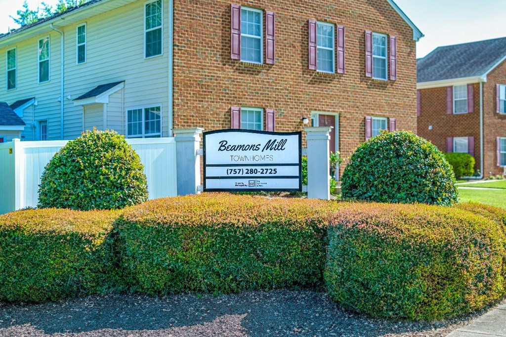 A sign for Beamons Mill Apartments is in front of a brick building.
