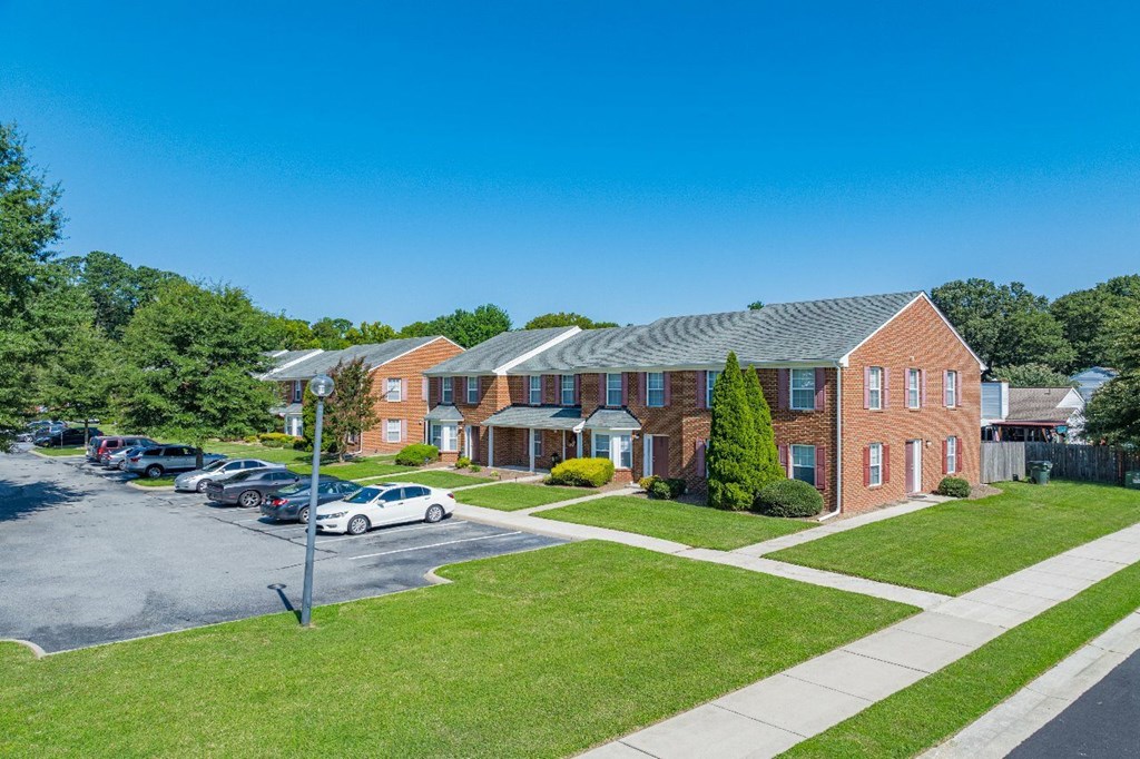 A parking lot in front of a red brick building.