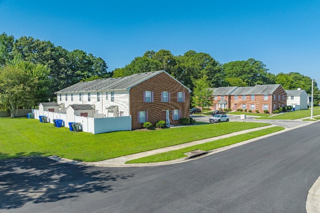A street view of a residential area with houses and trees.