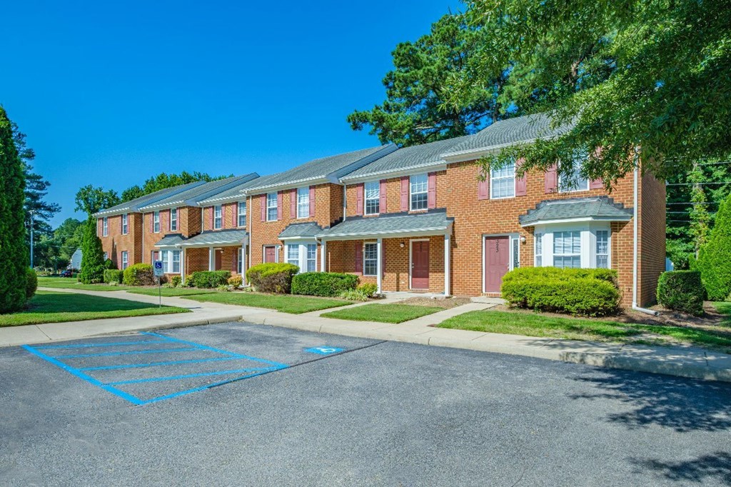 A row of red brick apartment buildings with a blue parking space in the foreground.