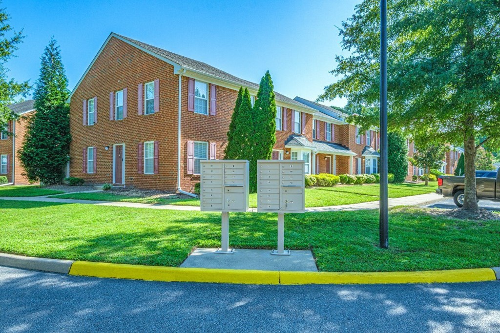 A street view of a residential area with a sign in the foreground.