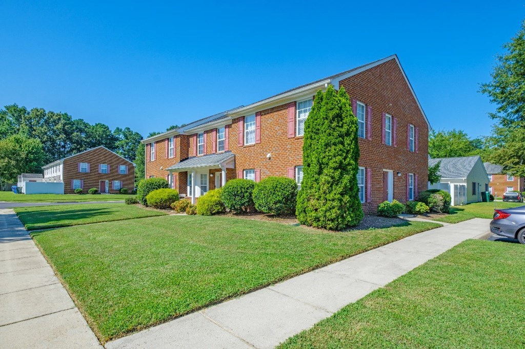 A red brick building with a green lawn in front.
