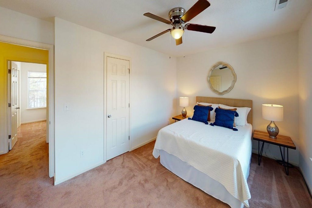 A bedroom with a bed, a ceiling fan, and a mirror.