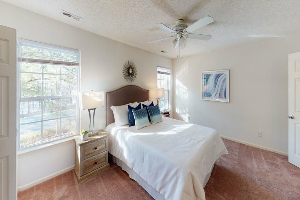 A bedroom with a bed, nightstand, and a ceiling fan.