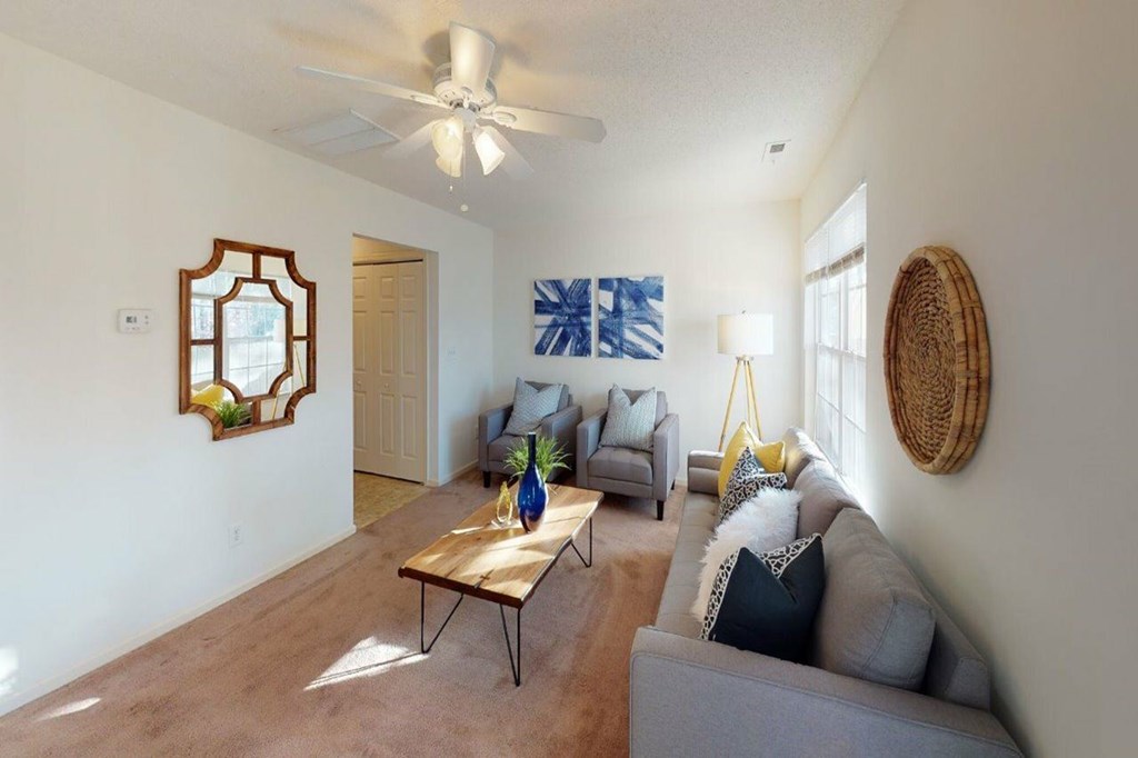 A living room with a grey couch, a wooden coffee table, and a ceiling fan.